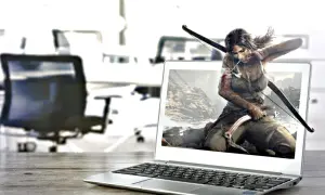 Lara Croft, postać z gry komputerowej, wychodzi z ekranu laptopa, gotowa do akcji z łukiem i czekana.
