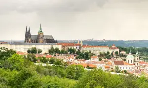 Widok na Zamek Praski i miasto z zielonymi drzewami na pierwszym planie.