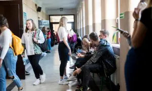 Uczniowie w szkolnym korytarzu, niektórzy siedzą, inni idą. Czy to sigma?