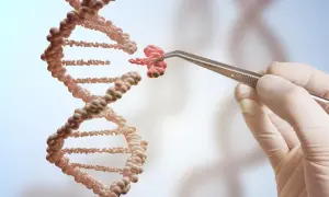 Ręka w rękawiczce trzyma pęsetą fragment DNA, jakby tworząc jego klon.