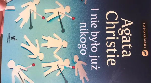 Okładka książki Agaty Christie "I nie było już nikogo". Papierowe ludziki z czerwonymi kropkami, jakby trafione.