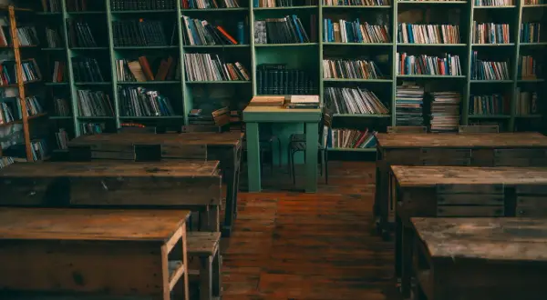 Stare ławki i regały pełne książek tworzą nostalgiczny motyw starej biblioteki lub klasy.
