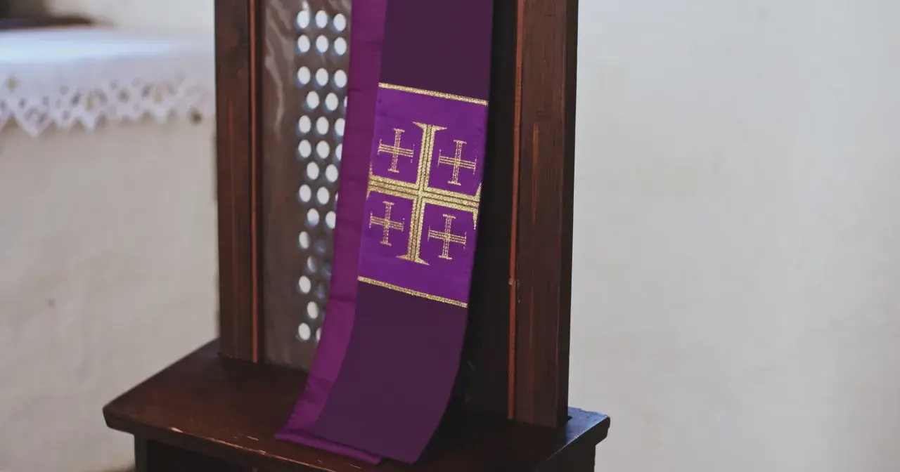 Fioletowa stuła z krzyżami, symbol sakramentu spowiedzi, wisi na drewnianej kratce konfesjonału.
