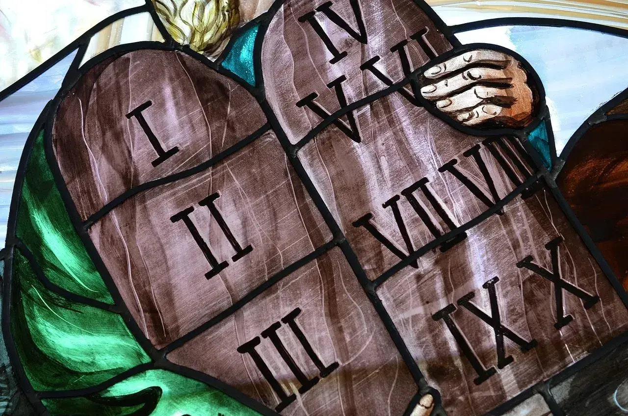 Witraż przedstawia kamienne tablice z rzymskimi cyframi, symbolizujące przykazania boże. Widoczne są cyfry I, II, III, IV, V, VI, VII, VIII, IX, X.