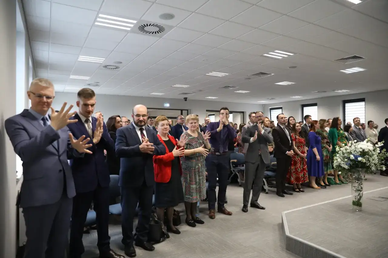 Ludzie w eleganckich strojach klaszczą, być może podczas spotkania świadków Jehowych.