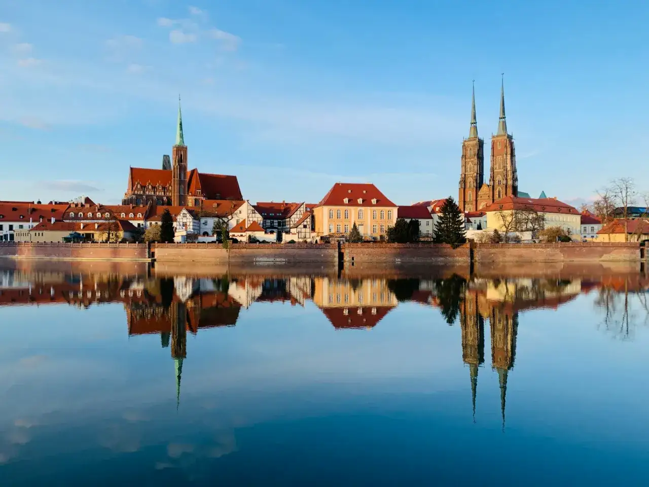 Piękne miasto na horyzoncie, z katedrą i innymi zabytkowymi budynkami, odbija się w spokojnej wodzie.