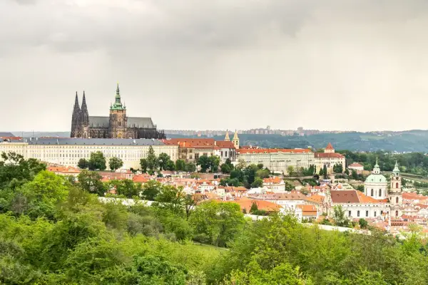 Widok na Zamek Praski i miasto z zielonymi drzewami na pierwszym planie.